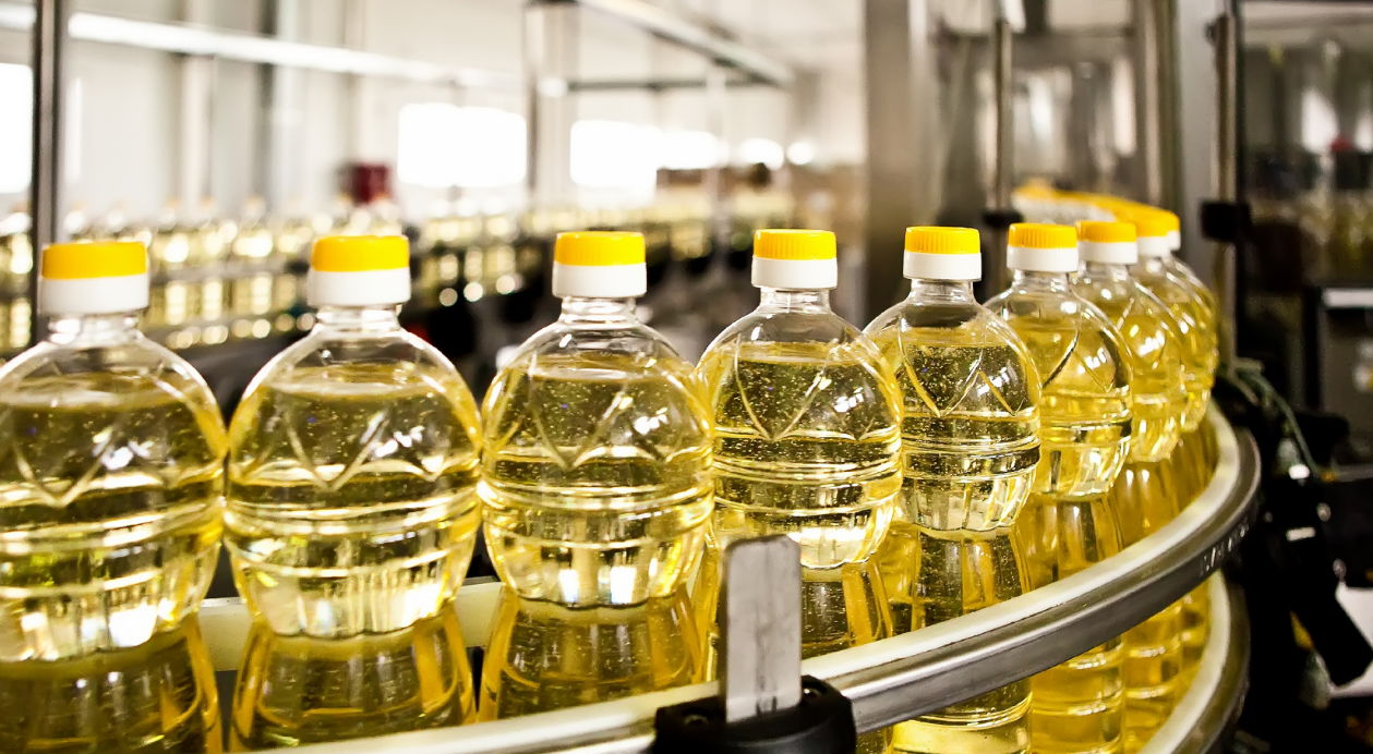 Clear PET bottles with yellow liquid and yellow caps on a production line.
