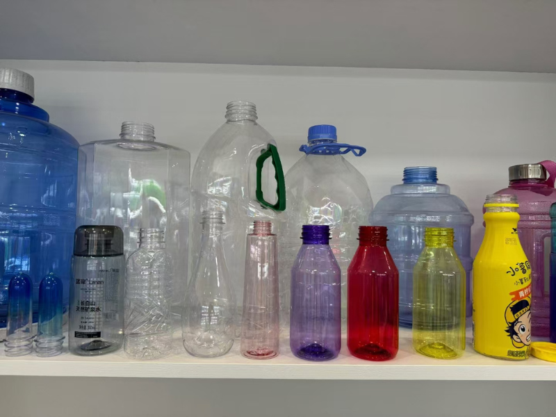Various plastic bottles in different sizes, colors (blue, transparent, yellow, etc.) displayed on a shelf.